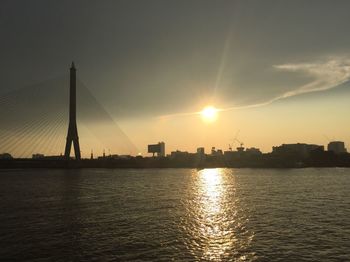 View of suspension bridge over river during sunset