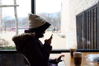 Side view of woman using phone in restaurant