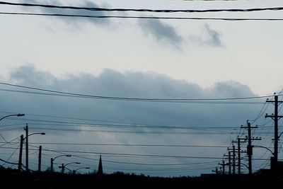 Low angle view of silhouette electricity pylon against sky