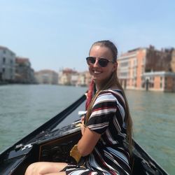 Side view portrait of smiling woman in boat on canal during sunny day