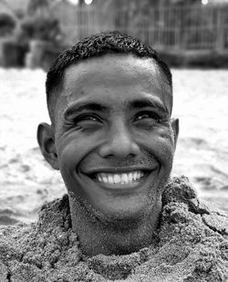 Portrait of smiling man buried in sand