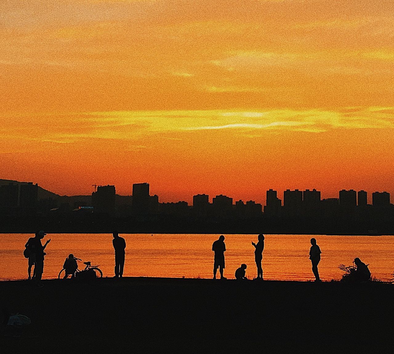 SILHOUETTE OF PEOPLE ON BEACH AGAINST SKY DURING SUNSET