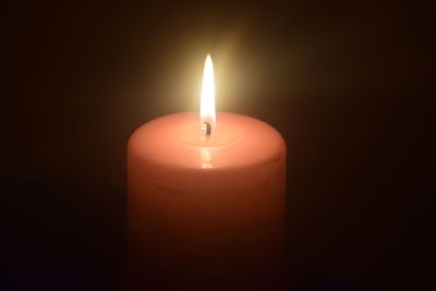 Close-up of lit candle in darkroom