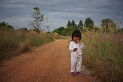 Portrait of cute girl standing on dirt road