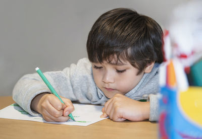 Portrait of boy holding eyeglasses on table