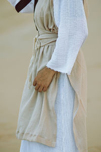 Midsection of woman standing against white wall