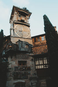 Low angle view of clock tower amidst buildings against sky