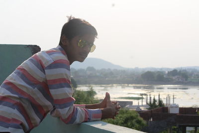 Side view of young man leaning on retaining wall at building terrace