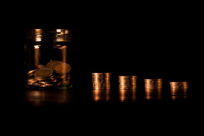 Close-up of illuminated candles on table against black background