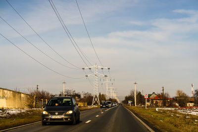 Cars on road against sky in city