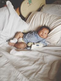 Portrait of cute baby boy with iv drip lying on bed at home