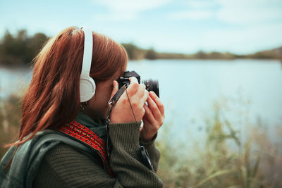 Portrait of woman photographing by lake
