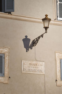 Low angle view of electric lamp on wall by building