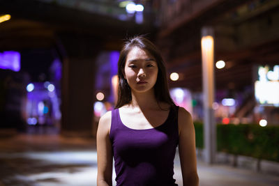 Portrait of woman standing in city at night