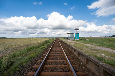 Railroad tracks on field against sky