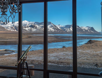 Panoramic view looking out windows on snow covered mountain range with an ocean bay