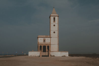 Lighthouse by sea against sky