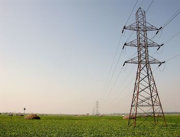 Electricity pylon on field against sky