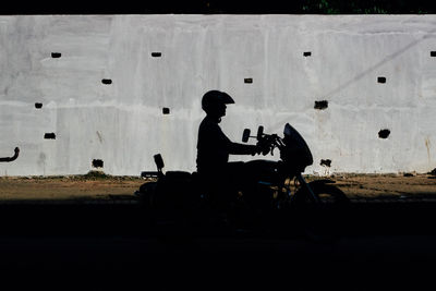 Side view of silhouette man sitting against sky