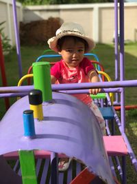 Close-up of toddler sitting on outdoor play equipment in playground