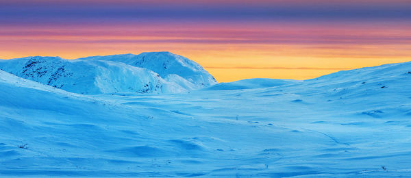 Scenic view of snowcapped mountains against sky during sunset