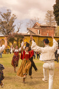 Rear view of people on field against sky