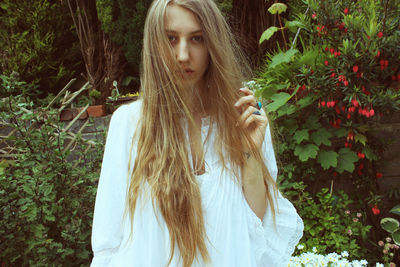 Portrait of young woman with long hair against plants
