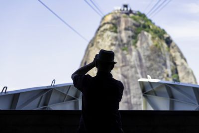 Low angle view of man standing by building against sky