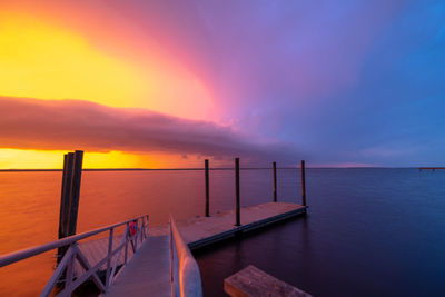 Pier over sea against sky during sunset