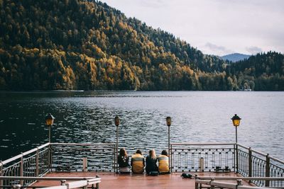 Rear view of friends sitting by lake