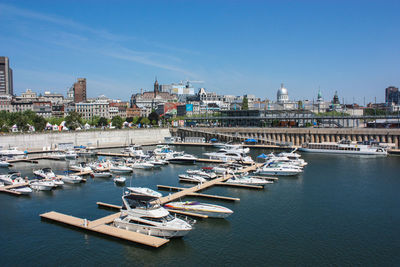 Boats in sea by cityscape against sky