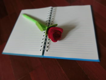 High angle view of artificial rose on book over table