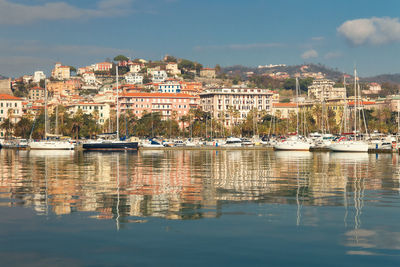 Sailboats moored at harbor against buildings in city