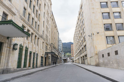 Empty road amidst buildings in city