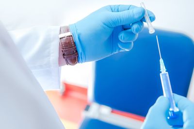 Close-up of person in lab coat holding syringe