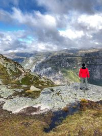 Rear view of man standing on mountain against sky