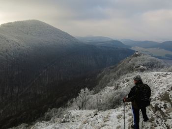 Rear view of person standing on mountain against sky