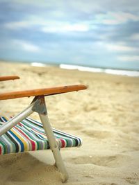 Chair on beach against sky