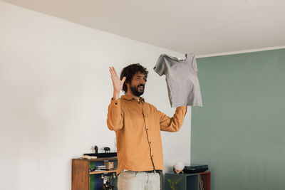 Caucasian young man plays with his daughter's t-shirt while folding clothes