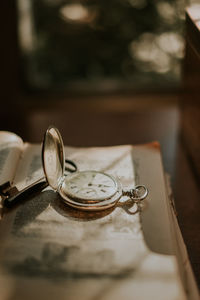 Vintage pocket watch placed on shabby page of aged book