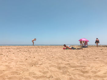 People on beach against clear sky