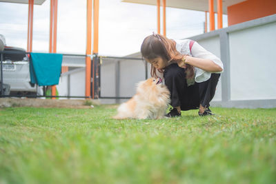 Woman with dog sitting on grass