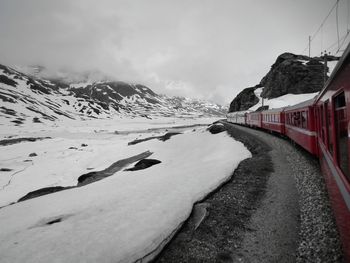 Train by glaciers and snowcapped mountains against cloudy sky