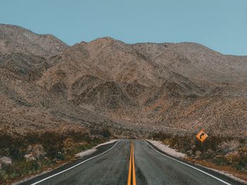 Road leading towards mountains against sky