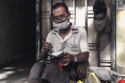 Rear view of senior man sitting on street