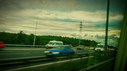 Cars on road against cloudy sky