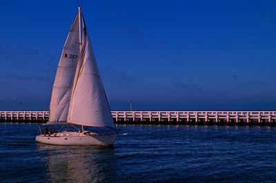 Sailboat sailing in sea against blue sky