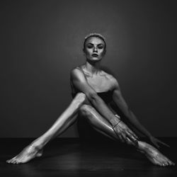 Portrait of woman sitting against wall on stage