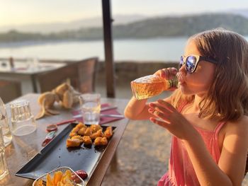 Portrait of young woman holding drink at beach