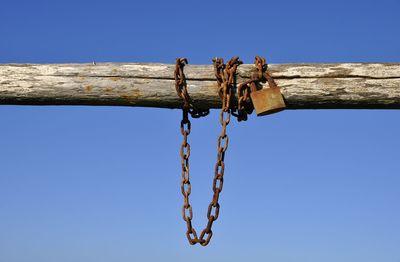 Low angle view of chain hanging against clear blue sky